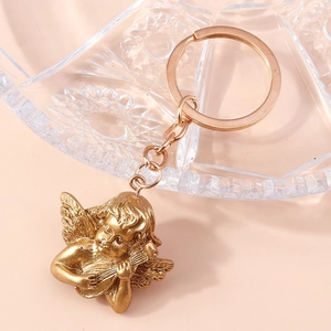 Detailed view of vintage gold angel keychain with harp on a decorative glass tray