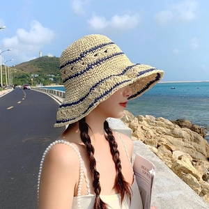 Handwoven beige straw sun hat with blue stripes, wide brim style for summer seaside beach travel
