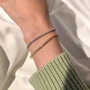 Close-up of silver and gold tennis bracelets with zircons on a model's wrist