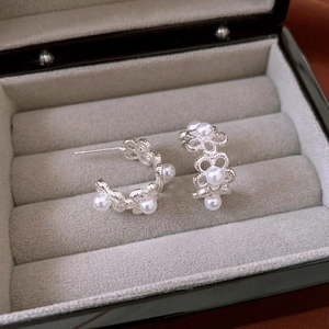 Detail of flower hollow earrings with white pearls in a premium gray velvet jewelry box