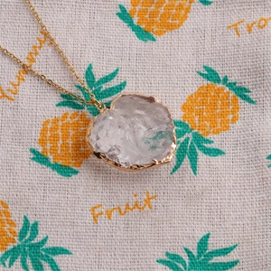Detail of a natural crystal pendant necklace with a gold-plated irregular moon stone