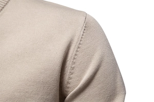 Detailed macro view of beige knit sweater shoulder seams and premium stitching texture