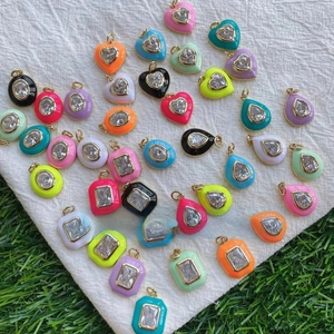 Macro shot of colorful enamel heart and geometric jewelry pendants with inset crystals