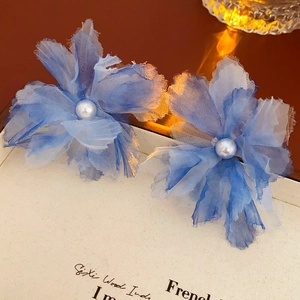 Detail view of blue organza flower hair clips with pearl centers and gradient pleats