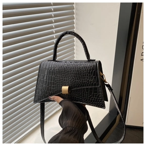Close-up of black crocodile embossed leather handbag with gold rectangular clasp