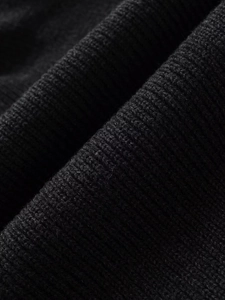 Macro shot of high-quality black rib-knit wool fabric texture on an asymmetric cloak coat