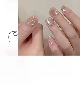 Short square press-on nails with nude gradient, white floral patterns and small rhinestones