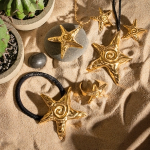 Parure bijoux étoile de mer dorée avec collier, boucles d'oreilles et bague sur sable