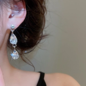 Close-up of elegant silver drop earrings with sparkling rhinestones worn by a model