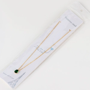 Close-up of teardrop emerald zircon pendant with gold chain on display card