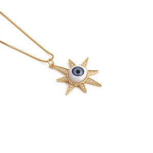 Détail d'un collier chaîne dorée avec pendentif œil maléfique étoilé et zircons brillants
