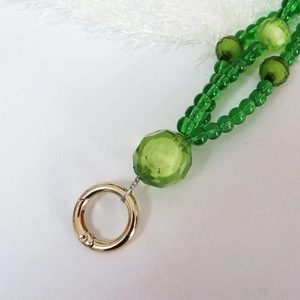 Detail of green acrylic beaded strap with faceted beads and gold metal spring ring