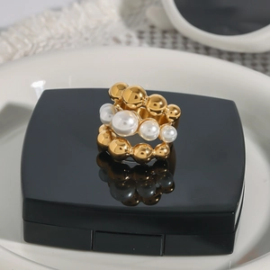 Detail of triple-layer gold bead ring featuring elegant white pearls on a black stand
