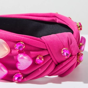 Detalle cercano de la diadema rosa con nudo, corazones de resina y brillantes cristales