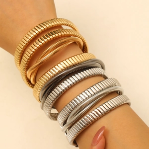 Dettaglio di bracciali elastici in metallo oro e argento con texture a strisce verticali