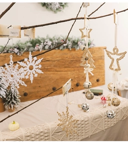 Close-up of white snowflake and gold star ornaments hanging on a Christmas tree branch