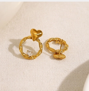 Macro shot of gold twisted hoop earrings with a heart shape and sparkling heart zircon