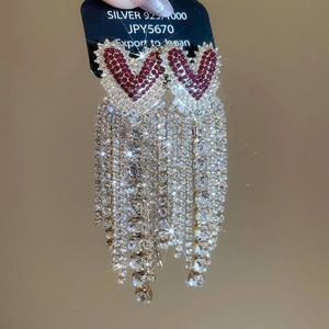 Close-up of silver 925 heart earrings with long sparkling tassel and red rhinestones