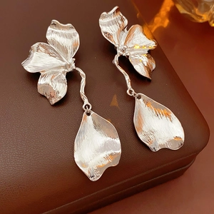 Macro shot of silver flower earrings with irregular petals and drop pendants on a jewelry box