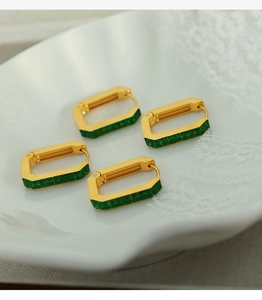 Macro shot of gold rectangle huggie earrings with emerald green zircon stones