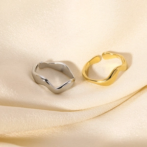 Dettaglio di anelli fluidi in oro e argento su un tessuto di seta beige chiaro