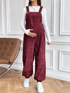 Detail of burgundy corduroy maternity overalls showing texture and adjustable side buttons