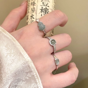 Detailed view of zircon gourd and flower rings worn on hand with vintage scroll