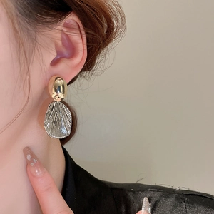Elegant gold and silver mixed metal shell textured drop earrings worn by a model