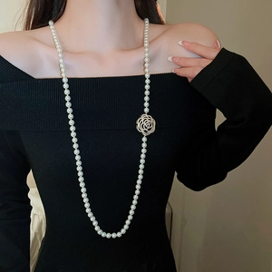 Détail d'un collier de perles élégant avec pendentif rose évidée et détails strass