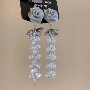 Macro detail of silver rose earrings with sparkling crystal tassels on jewelry card