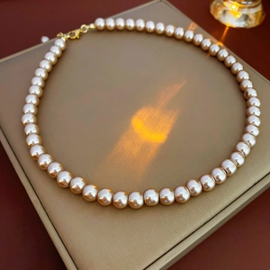 Detail of single strand champagne pearl necklace with gold clasp on premium display box