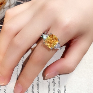 Anillo clásico de plata con gema amarilla talla radiant usado sobre una revista