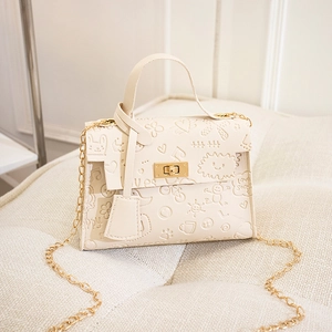 Detail of beige textured shoulder bag featuring heart embossed patterns and gold lock