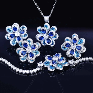 Macro shot of silver-tone jewelry set featuring blue and clear zircon floral motifs