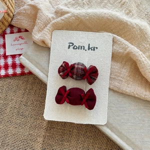 Detail of candy-shaped fabric hair clips in burgundy red with bow and ribbon accents