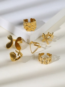 Set of six gold-plated coastal rings featuring starfish and butterfly charms on a white stand