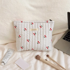 Detail of white quilted toiletry bag with cherry prints and zip closure