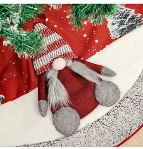 Detail of Christmas gnome plush with striped hat and white beard on a red tree skirt