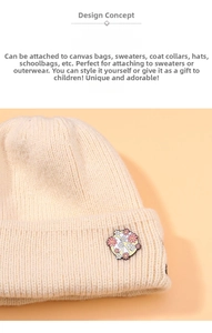 Close-up of a pink and yellow flower enamel pin on a cream knitted beanie hat