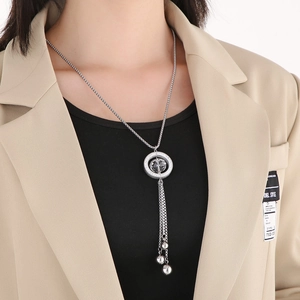Detail of silver tassel pendant necklace with metal balls on a female model wearing a blazer