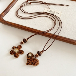 Vue détaillée du collier pendentif cœur léopard rétro sur un plateau en bois