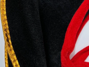 Detail view of black velvet pirate costume with red faux fur and gold trim texture