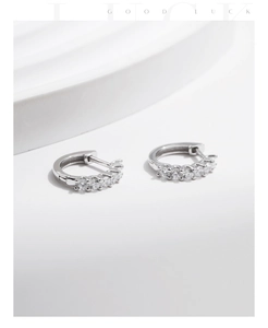 Detail of silver S925 huggie earrings with five sparkling round-cut stones on white base