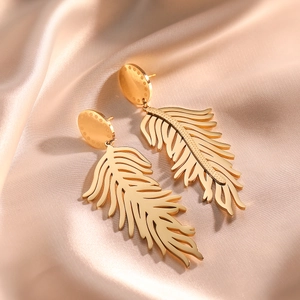 Golden feather earrings in leaf shape on champagne silk background for women