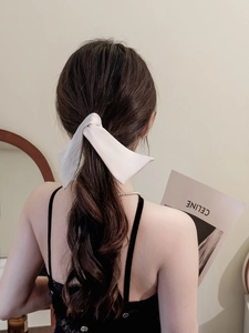Dettaglio dell'elegante fermaglio per capelli in raso crema per una coda di cavallo bassa