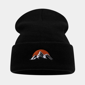 Détail du bonnet noir montrant la broderie de montagne enneigée et la maille épaisse