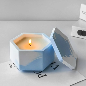 Modern hexagonal blue marble textured cement candle jar with lid and lit candle