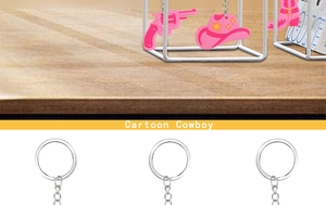 Close-up of pink PVC cartoon cowboy charms featuring guitar, hat and boots on silver chain
