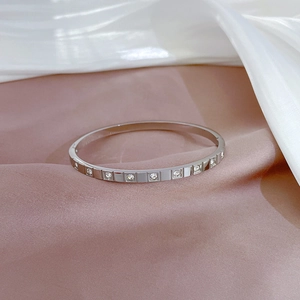 Macro detail of silver titanium steel bangle featuring square pavé-set rhinestones