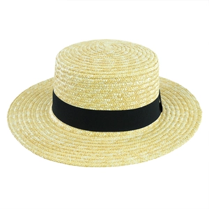 Dettaglio di un cappello di paglia intrecciato con nastro nero su sfondo bianco